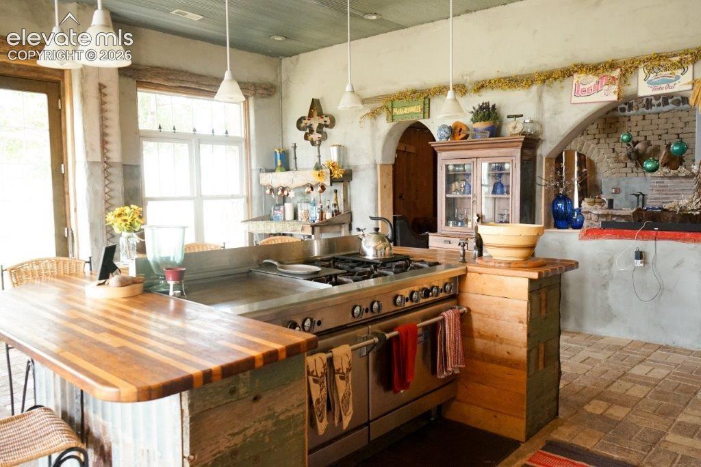 Industrial-style kitchen featuring a professional-grade range, stainless steel countertops, and a butcher block island