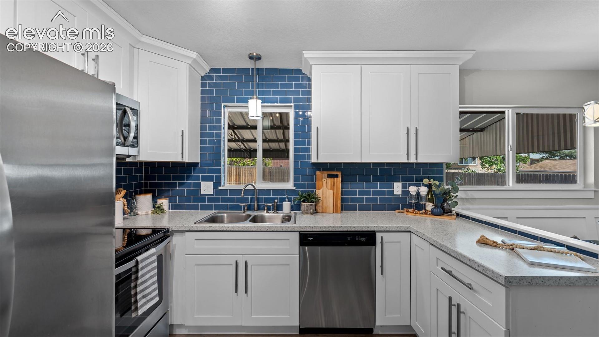 Kitchen featuring white cabinetry, stainless steel appliances, a tile backsplash, and light-toned countertops