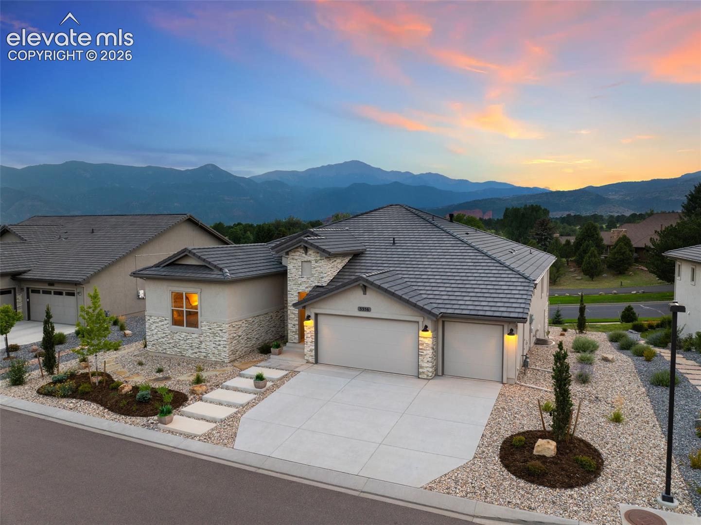 Contemporary exterior with a tile roof, stone and stucco facade, and an attached two-car garage