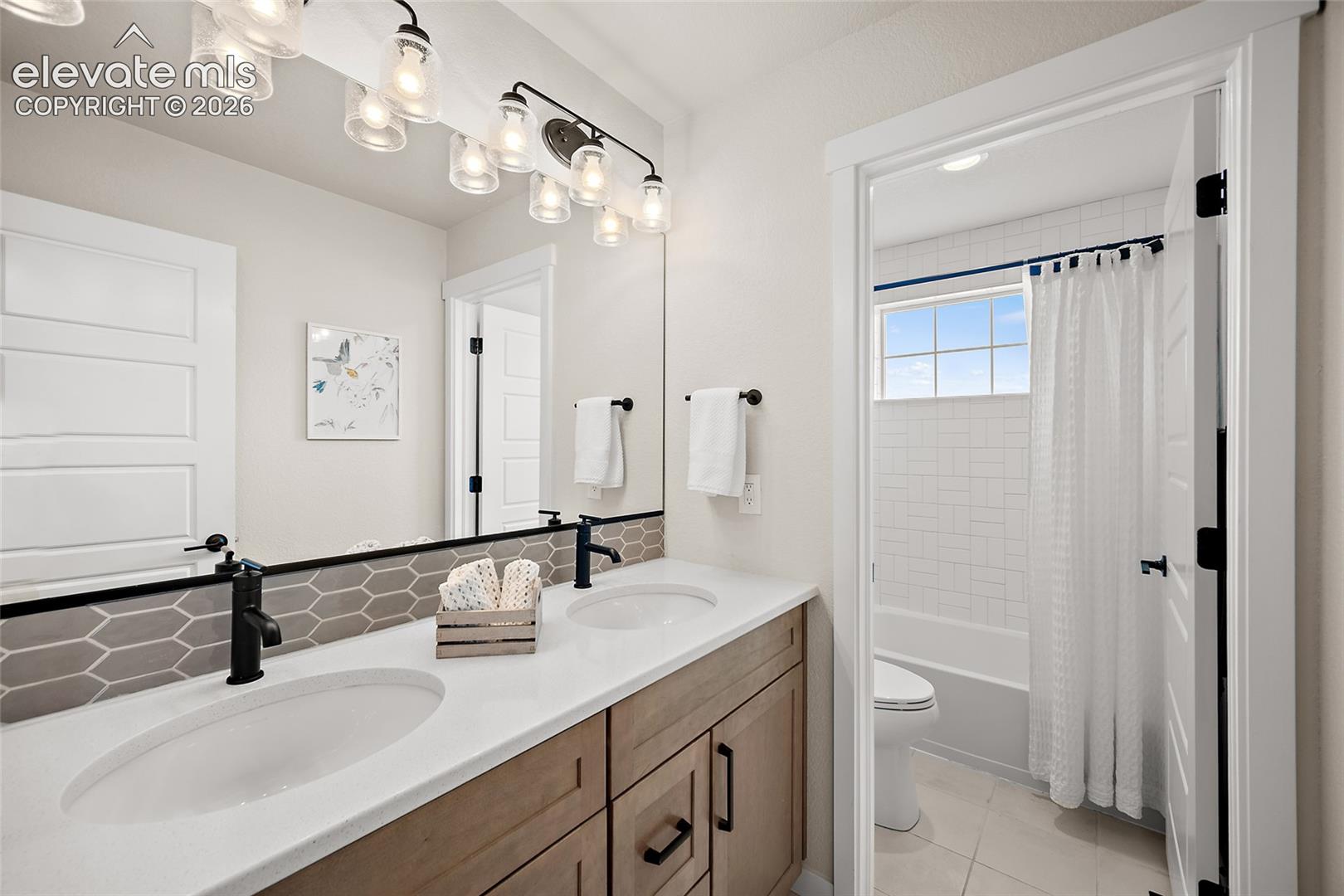 Double vanity with white countertops, wood-finish cabinetry, and matte black fixtures
