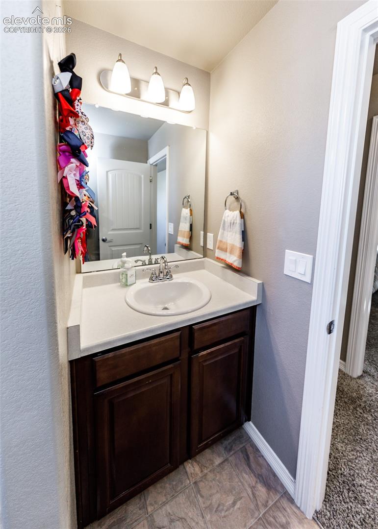 Bathroom vanity featuring a dark wood-finish cabinet, solid-surface countertop with an integrated oval sink, chrome faucet, three-bulb vanity lighting fixture, and a large plate-glass mirror