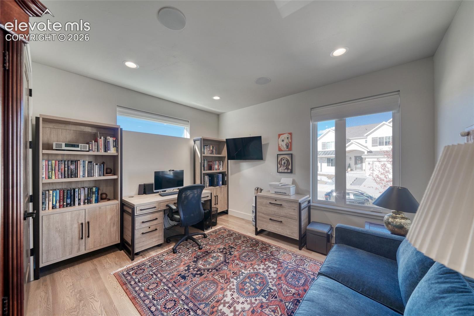 Built-in shelving units with lower cabinet storage, recessed lighting, and wood-finish flooring