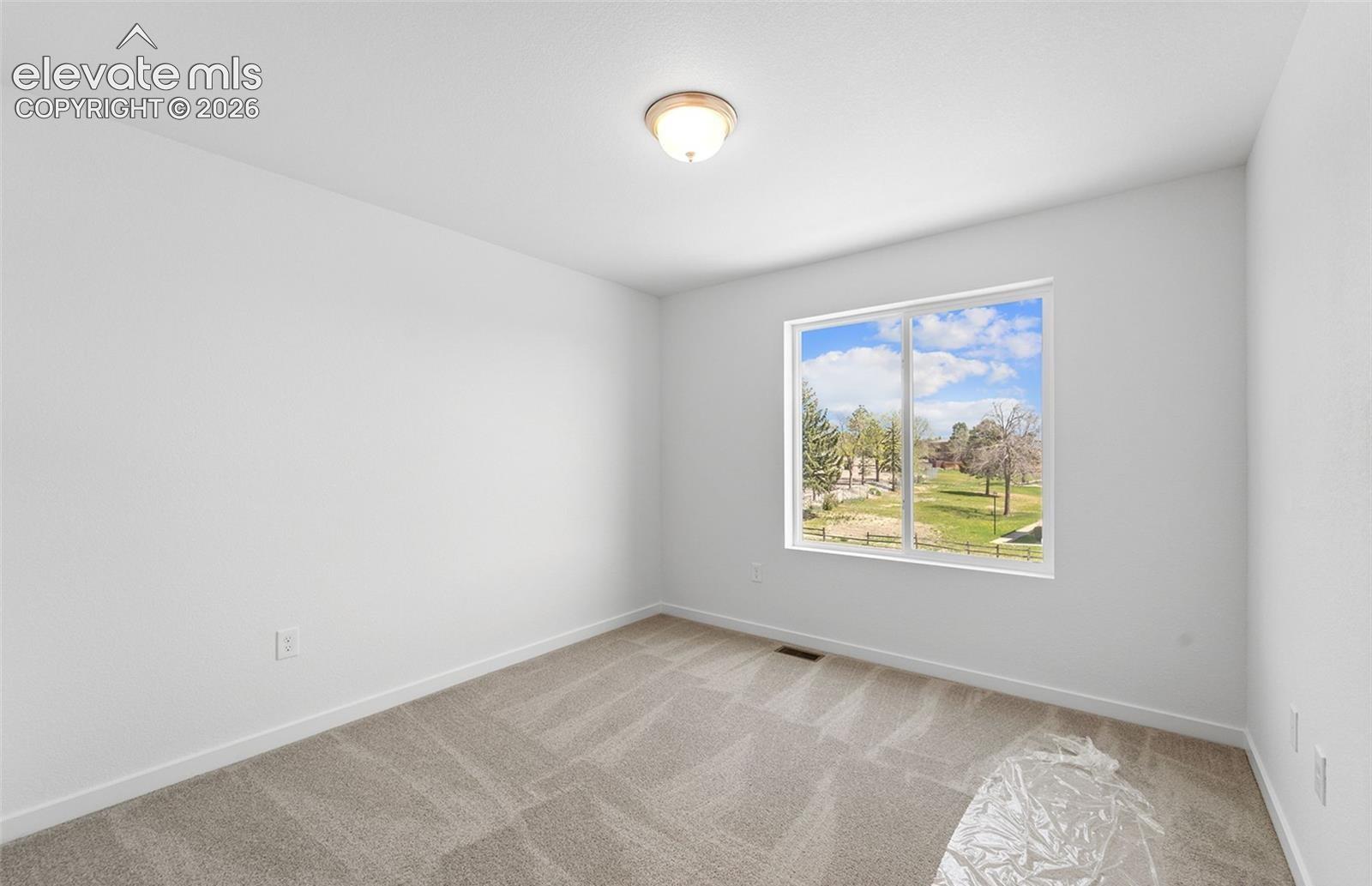 Neutral interior with carpeted flooring, white walls, flush-mount ceiling lighting, and a large window