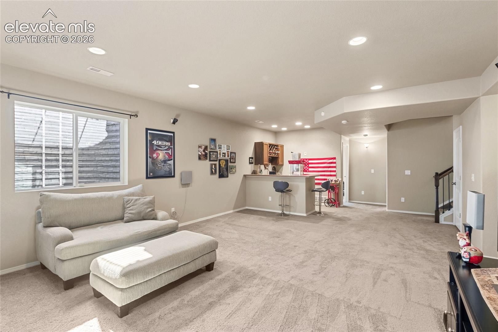 Open floor plan featuring recessed lighting, carpeted flooring, and a built-in wet bar with cabinetry