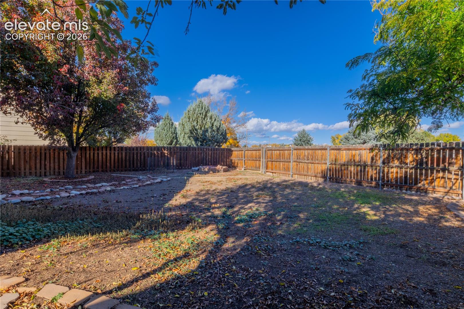 A spacious, fenced outdoor retreat with mature trees and room to make the space your own.
