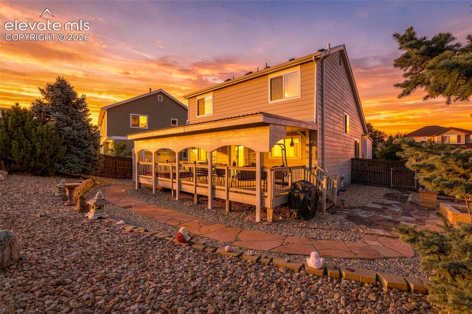 Covered outdoor deck with white railing, leading to a stone patio