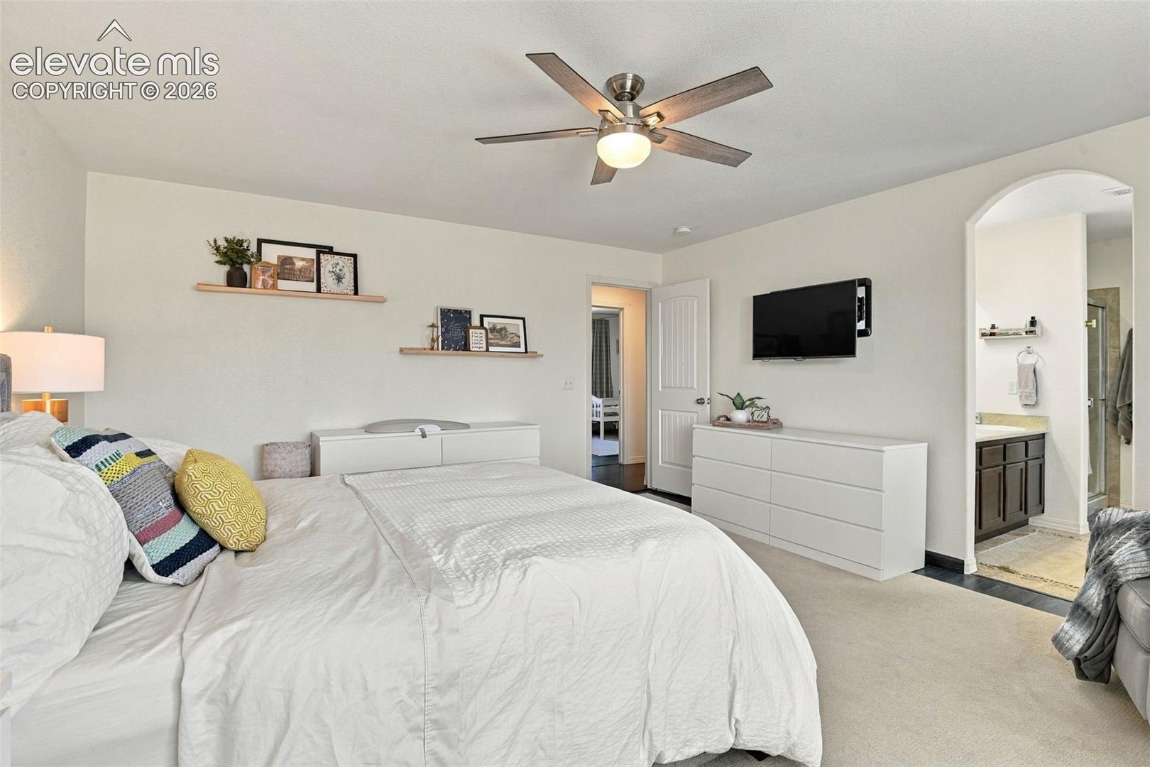 Recessed lighting, ceiling fan with light fixture, arched doorway, vanity with dark wood-finish cabinetry, and glass-enclosed shower