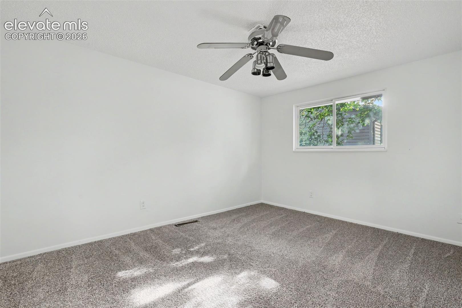 Upper level bedroom with ceiling fan and new carpet.