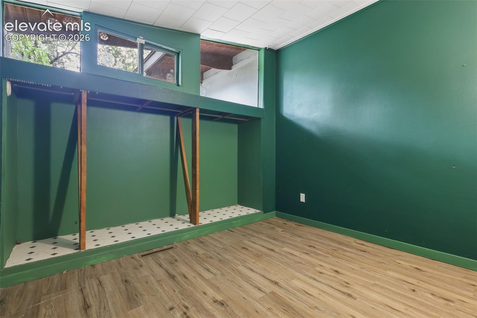 Wood-finish flooring, built-in shelving, high transom windows, and a drop ceiling
