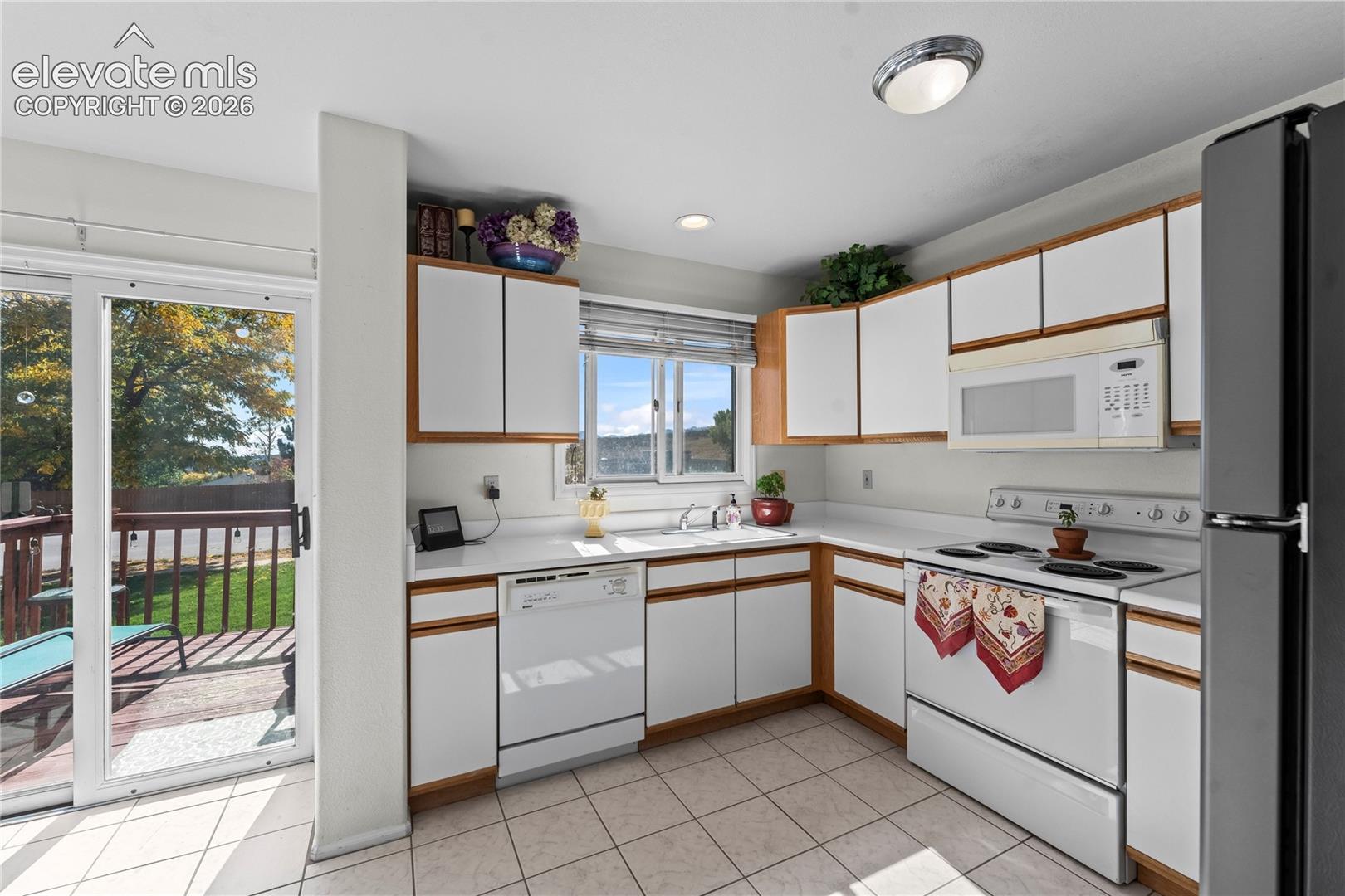 Kitchen featuring white cabinetry with wood-finish trim, white countertop, and tile flooring
