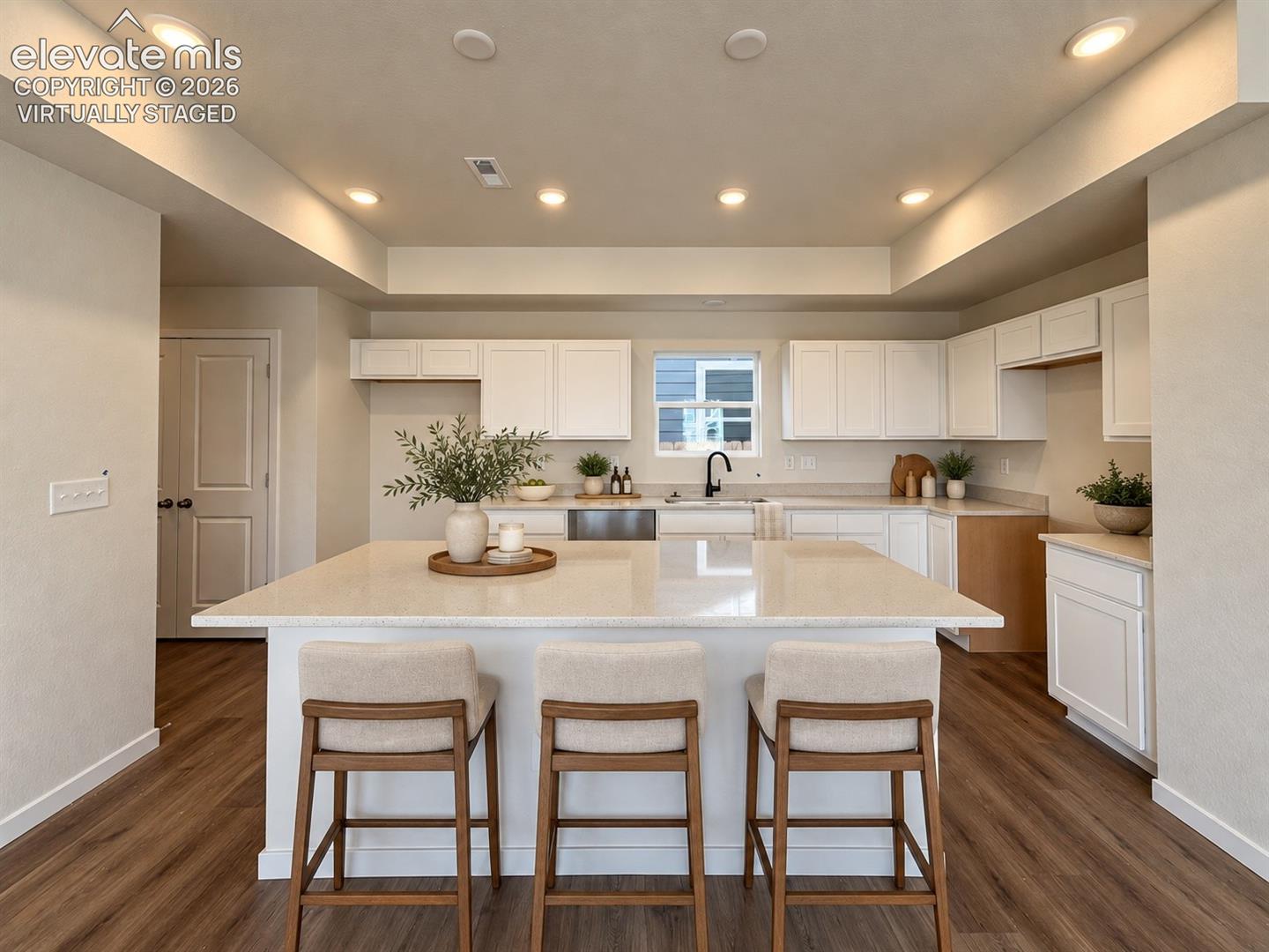 kitchen with large island, white cabinetry, recessed tray ceiling, and wood-look floors — virtually staged