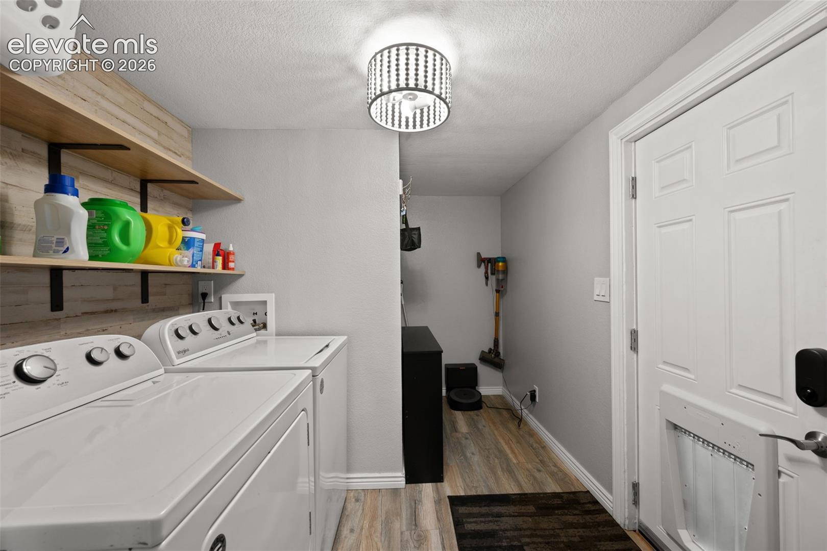 Utility room featuring wood-finish flooring, floating wood shelving with matte black supports, and a semi-flush mount drum light fixture