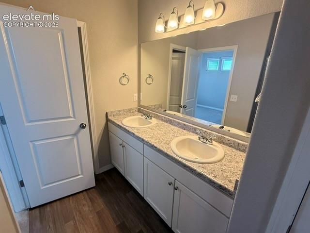 Double vanity with light-colored countertop and two integrated sinks, set upon white cabinetry, illuminated by a four-light fixture