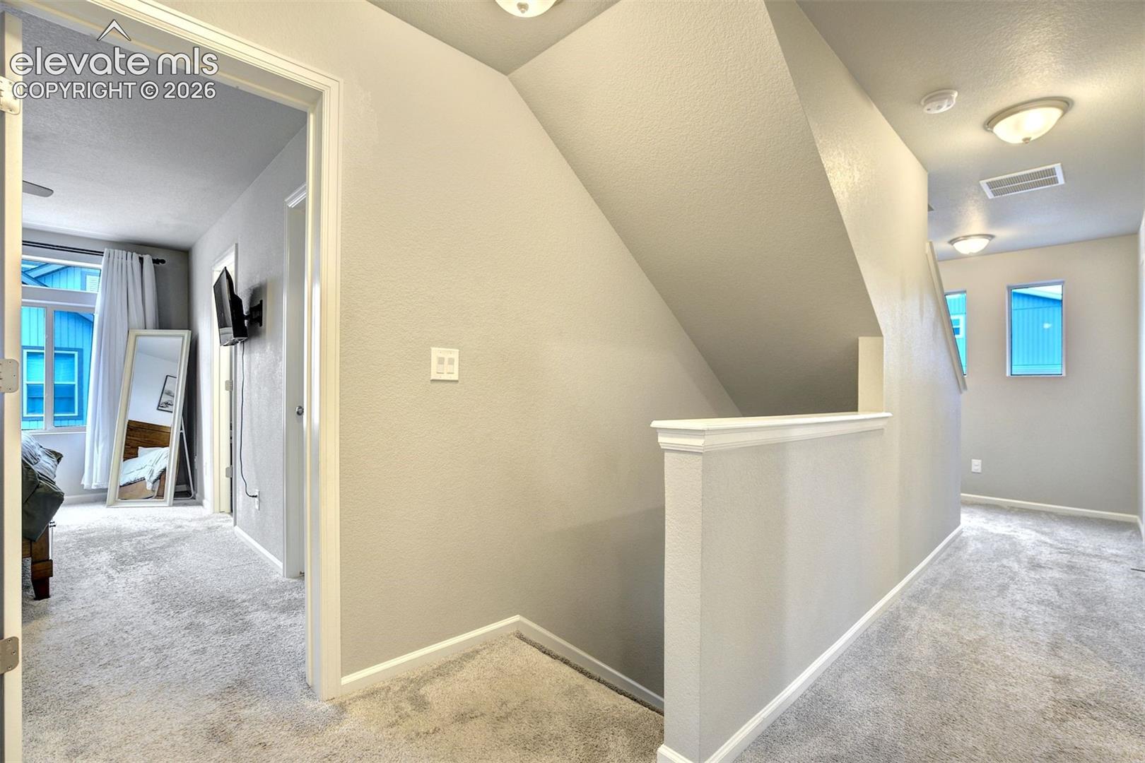 Upper-level landing featuring neutral wall-to-wall carpeting, recessed ceiling lighting, and a partial-height staircase partition wall