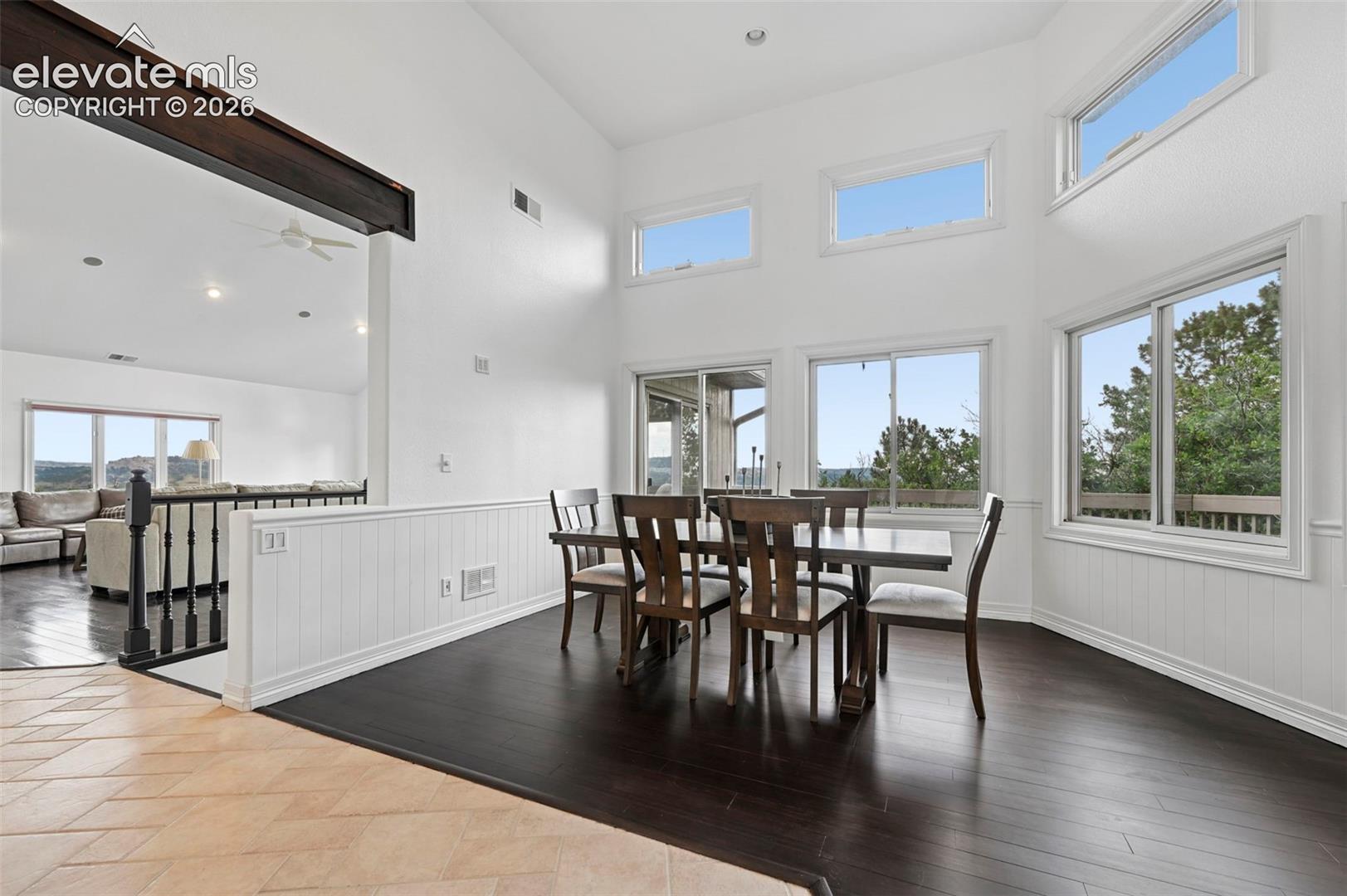 Vaulted ceilings and abundant natural light highlight this dining area with dark wood-finish flooring and wainscoting