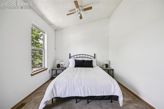 Carpeted bedroom with a textured ceiling and a ceiling fan