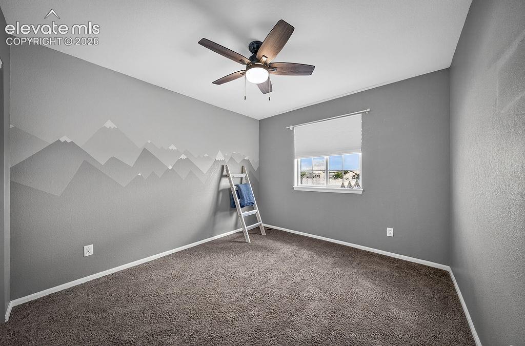 Wall-to-wall carpeting, ceiling fan with integrated lighting, and a single window with a roller shade