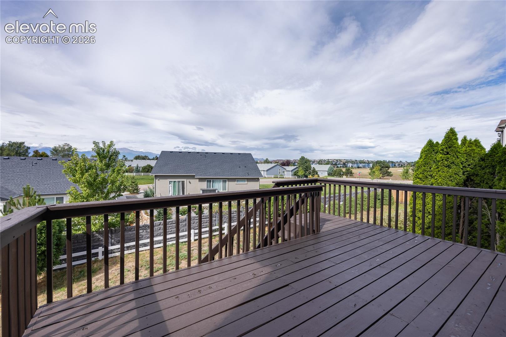 Expansive outdoor deck with wood-finish railing and decking, offering distant mountain scenery