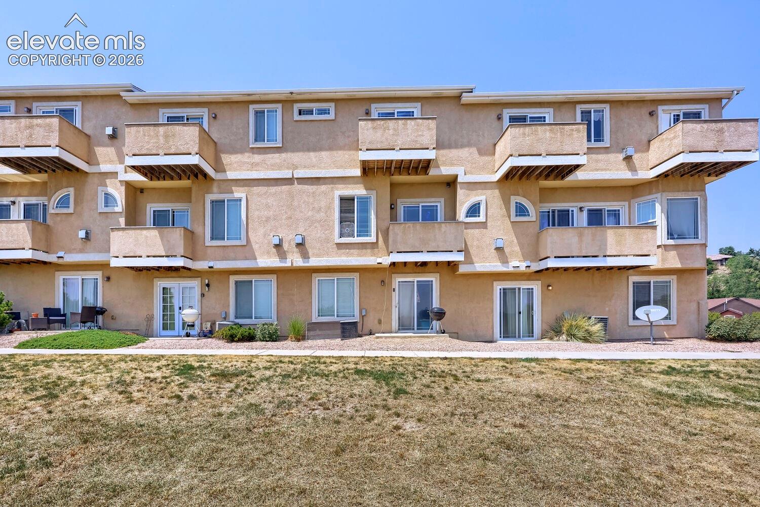 Multi-story stucco exterior featuring multiple balconies and ground-level patios