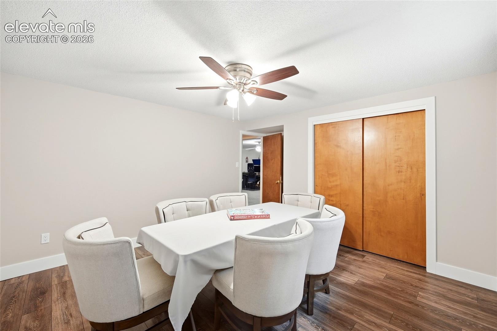 Interior space featuring wood-finish flooring, a ceiling fan with integrated lighting, and dual wood-panel closet doors