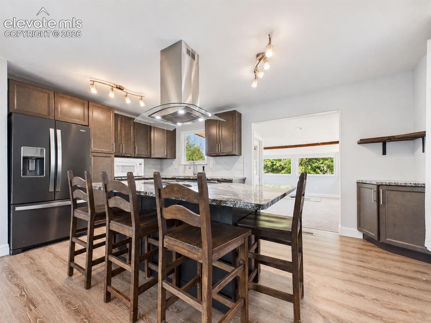 Another angle highlights the generous island seating, abundant cabinetry, and modern lighting, with the added sunroom opening directly off the kitchen for additional flexible living space.