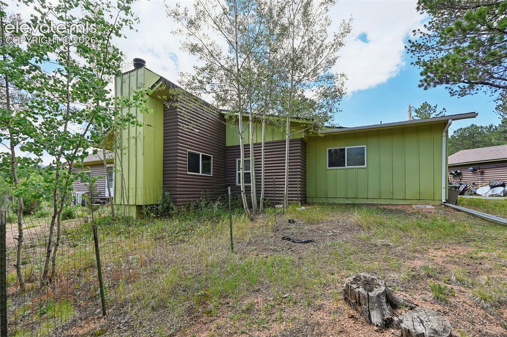 Side exterior featuring vertical green siding and horizontal brown siding
