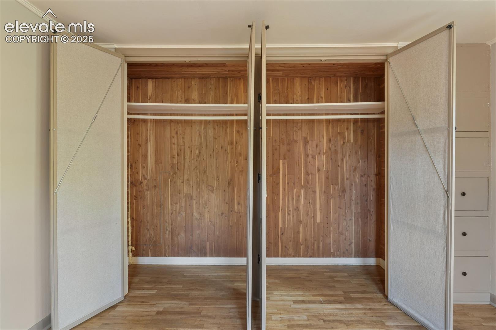 Dual bi-fold closet doors open to reveal a cedar-lined interior with upper shelving and hanging rods