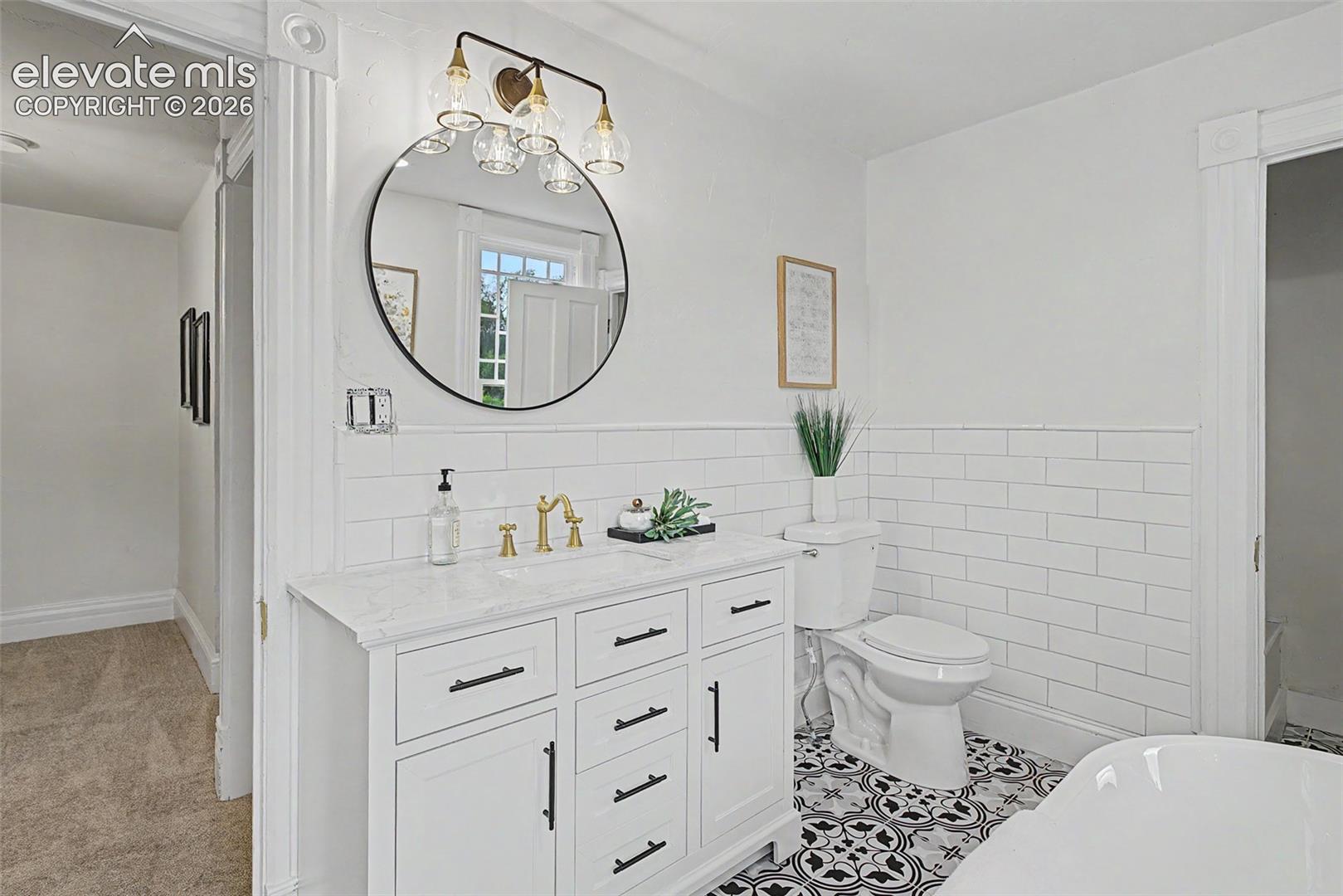 Bathroom featuring a white vanity with a light-toned countertop, black hardware, and a circular mirror