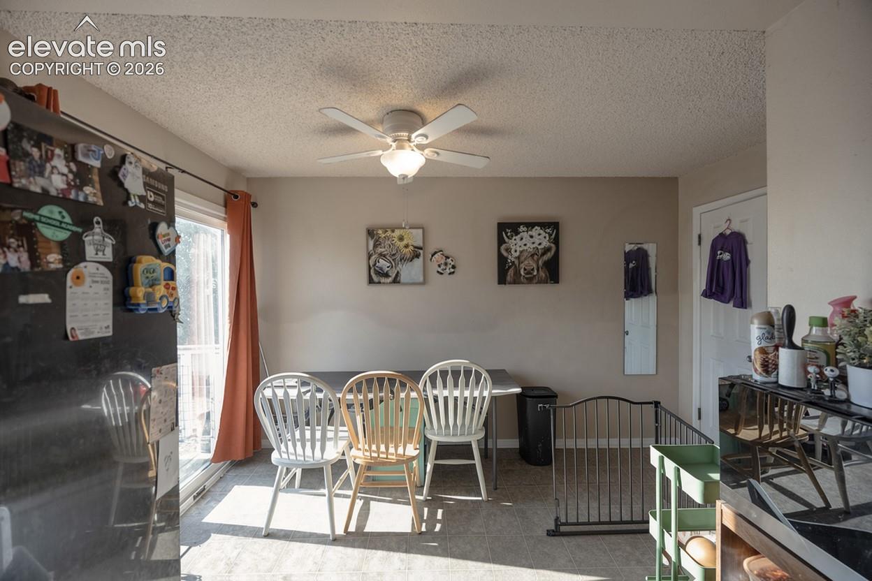 Sliding glass door, neutral wall paint, ceiling fan with integrated lighting, textured ceiling, and wood-finish flooring