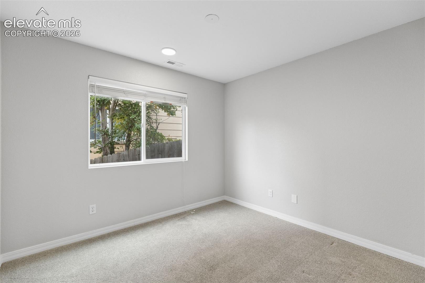 Neutral interior featuring neutral-toned carpeting, recessed ceiling lighting, and a window with horizontal blinds