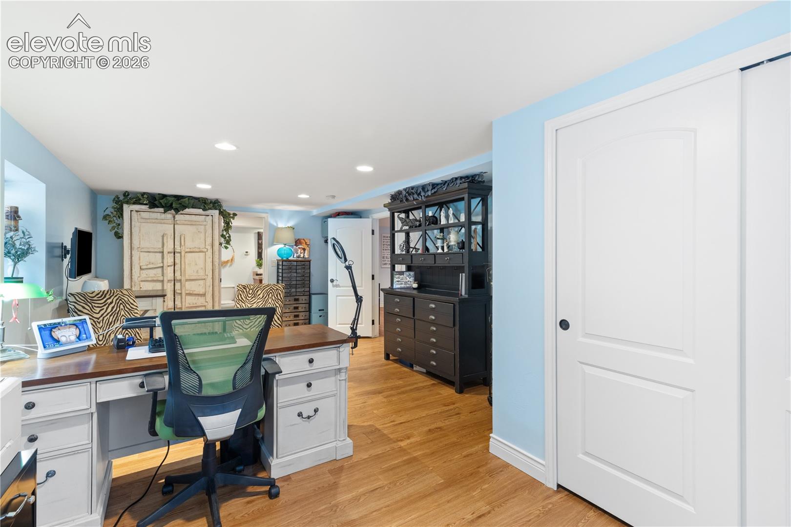 Versatile room featuring wood-finish flooring, recessed lighting, a built-in hutch, and a sliding panel door