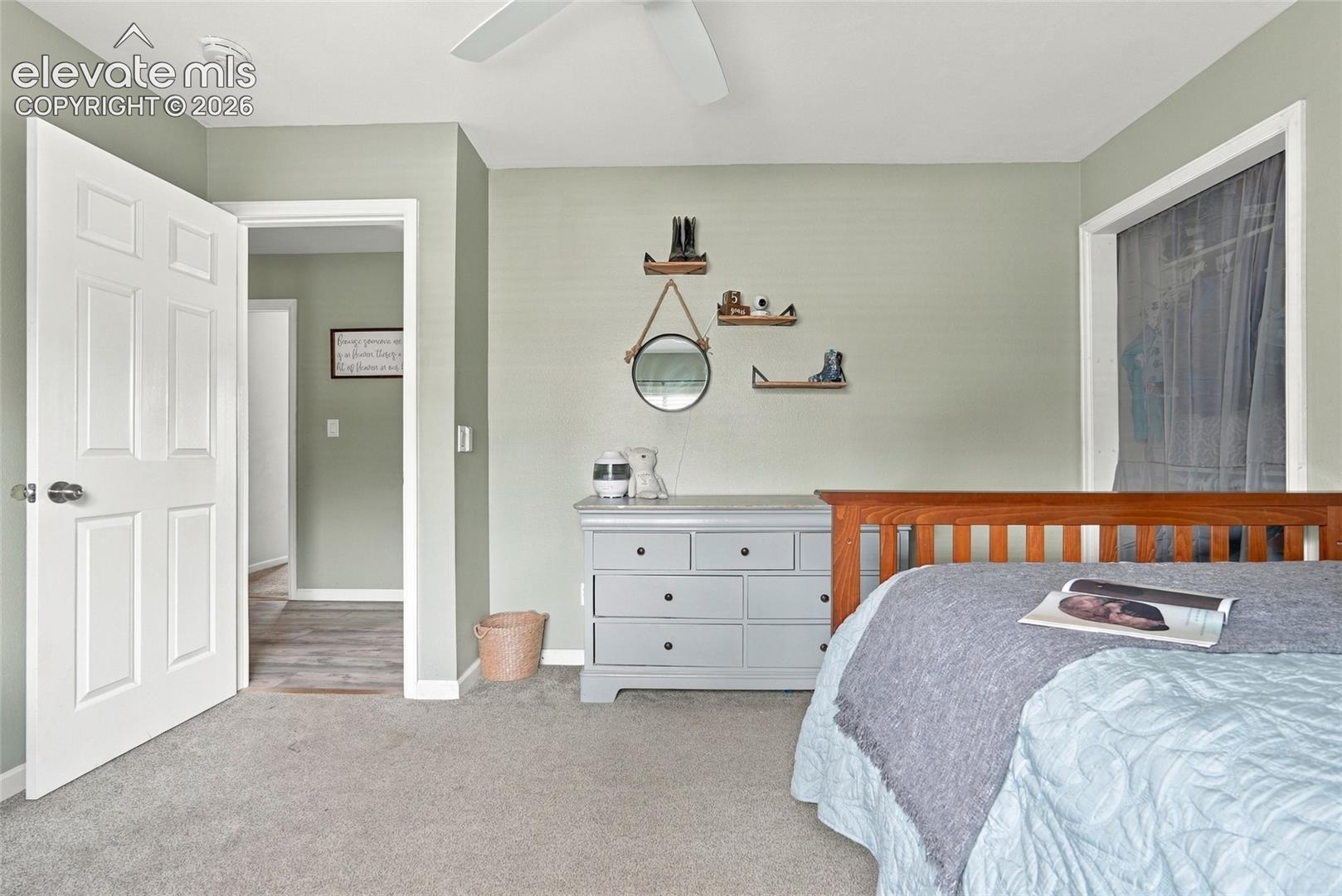 Wall-to-wall carpeting, paneled interior door, and a ceiling fan