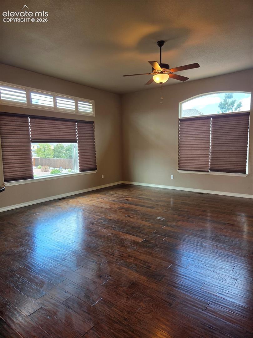 open-Spacious living room featuring wood-finish flooring, a ceiling fan with integrated lighting, and multiple windows with privacy blinds and walk out to patio .