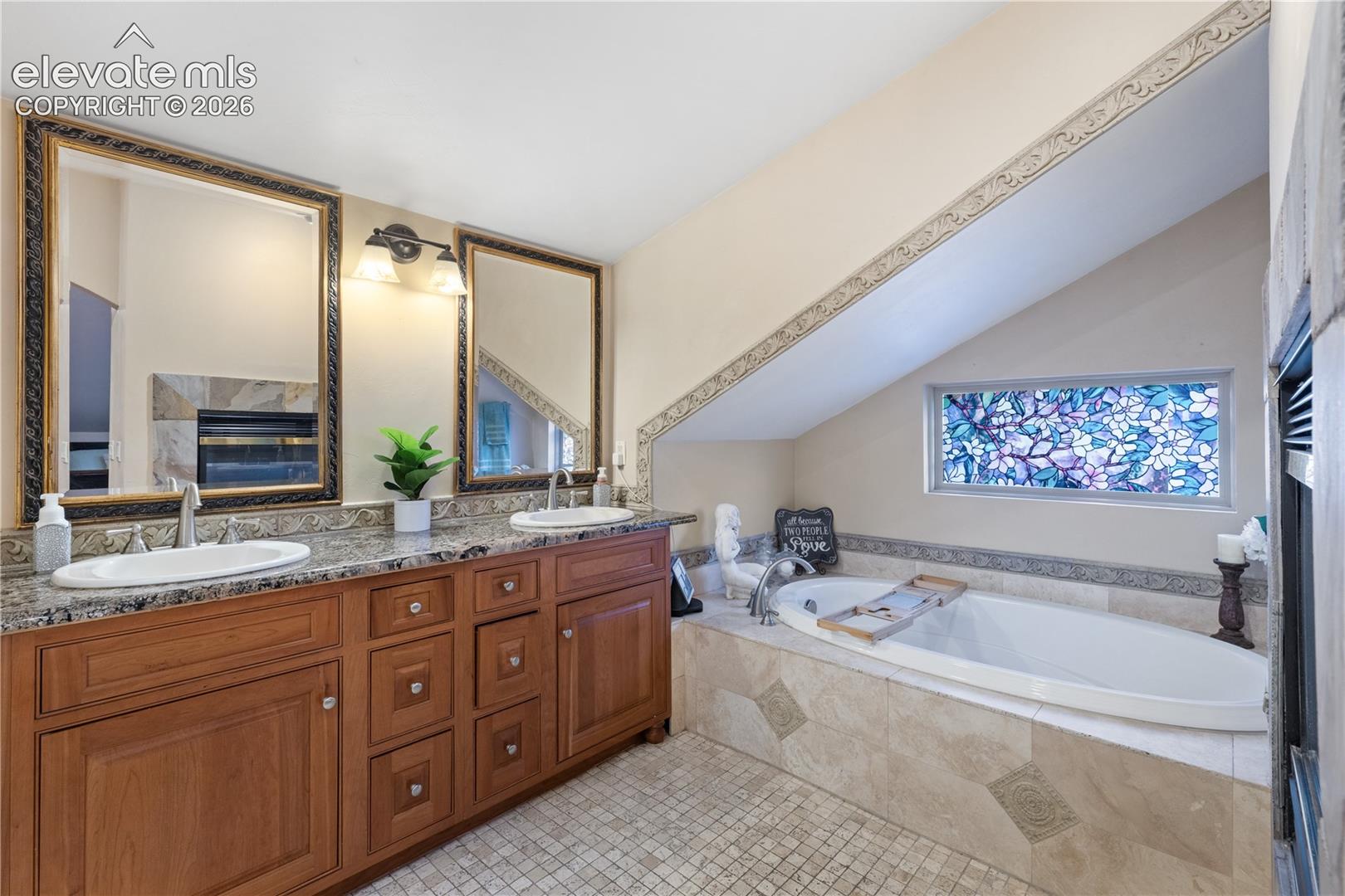 Bathroom featuring a dual vanity with granite countertops, undermount sinks, and wood cabinetry