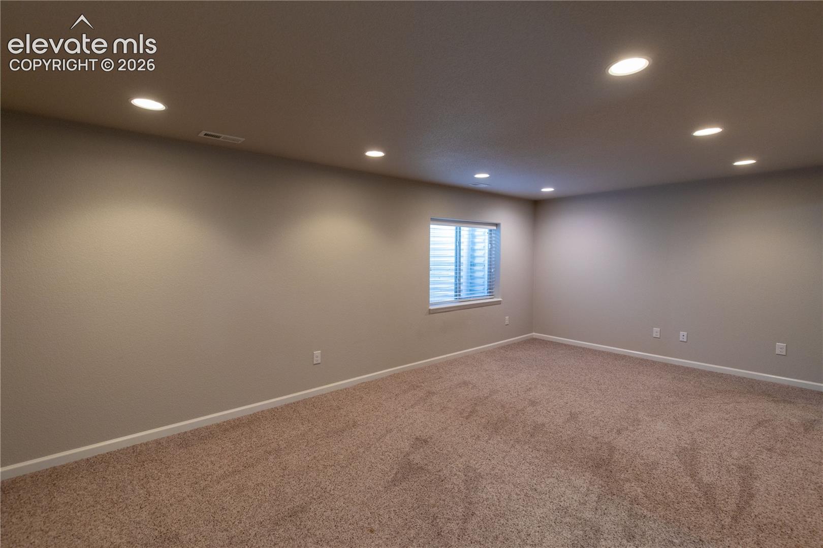 Neutral interior room featuring recessed ceiling lighting, carpeted flooring, and a single window with blinds