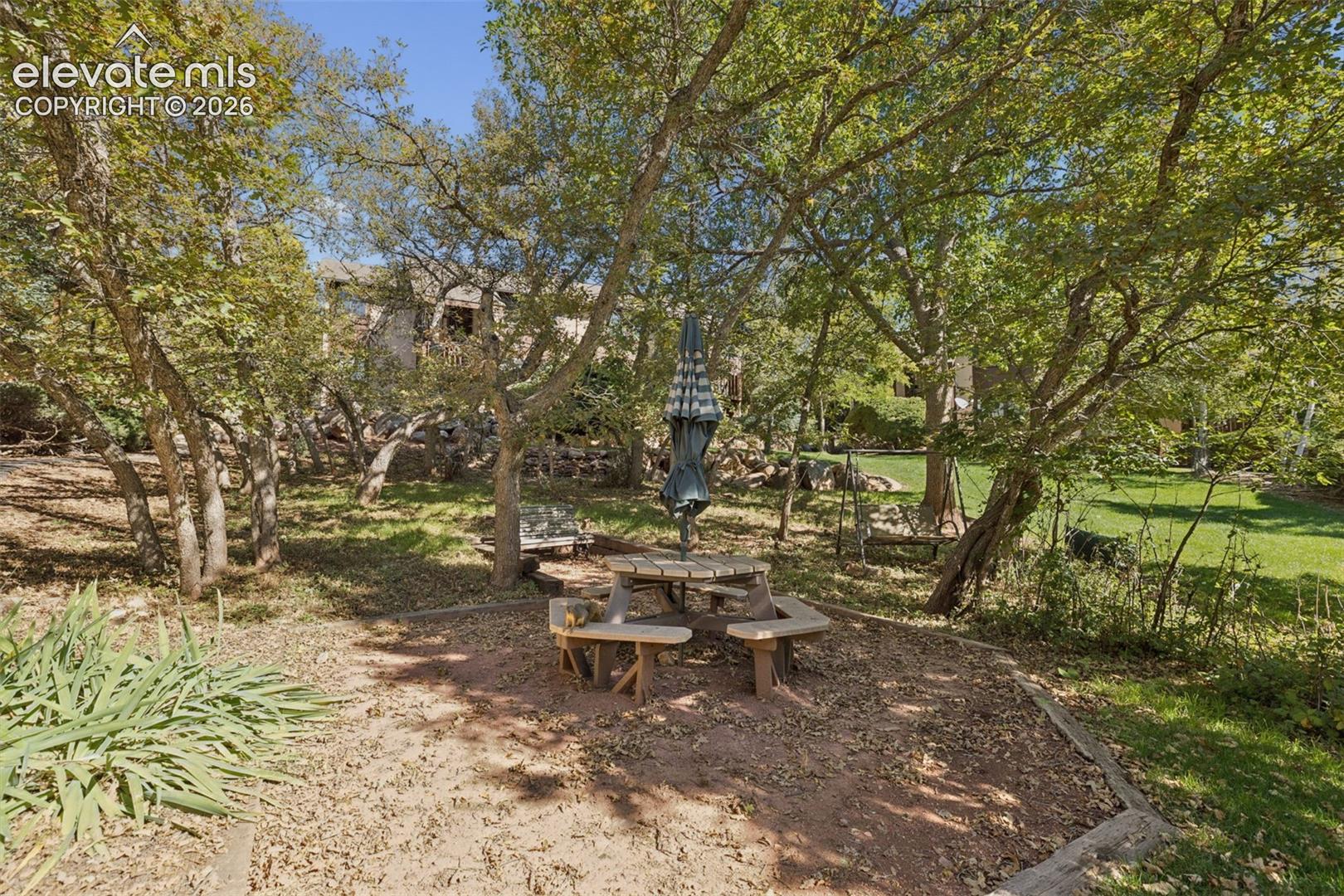 Expansive outdoor area featuring mature trees, a picnic table, and a manicured lawn