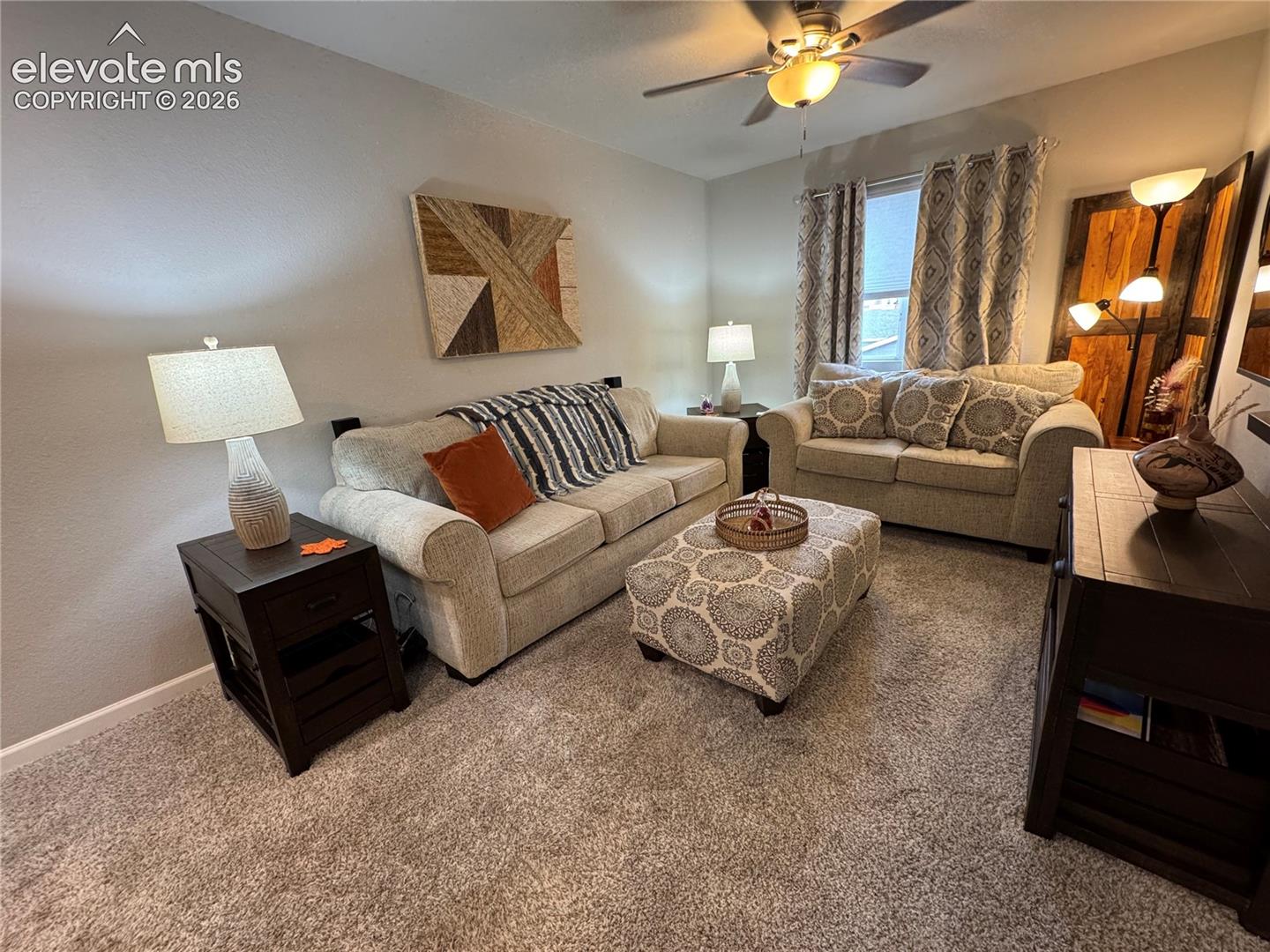Neutral wall finishes, plush carpeting, and a ceiling-mounted light fixture with integrated fan