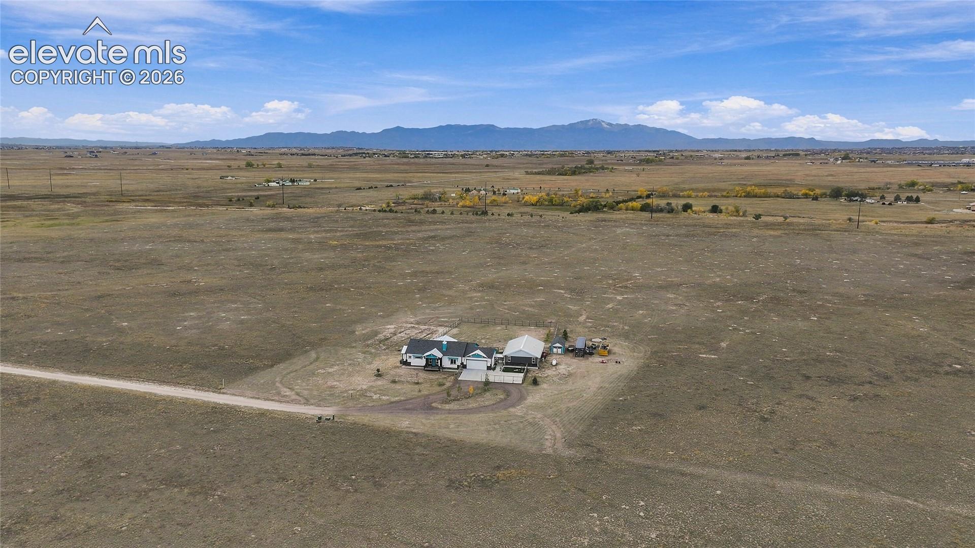 Expansive acreage featuring a multi-structure property, paved driveway, and mountain scenery
