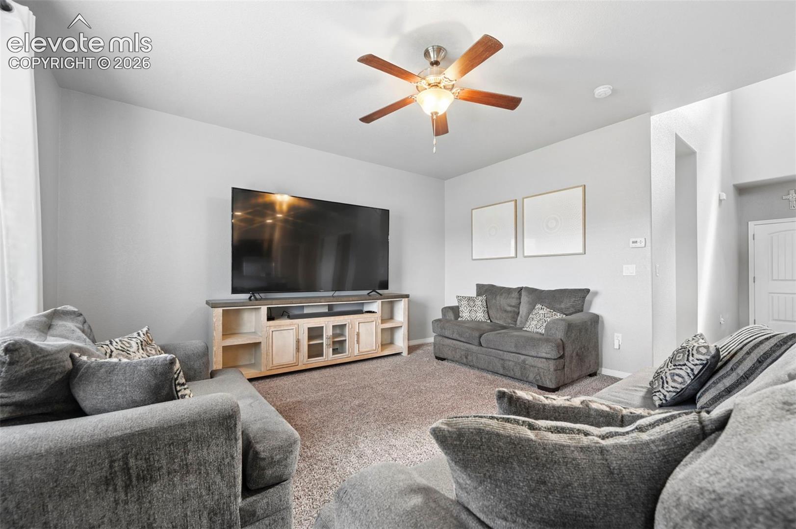 Recessed lighting, ceiling fan with light fixture, light gray walls, carpet flooring, and a built-in media console with cabinet storage