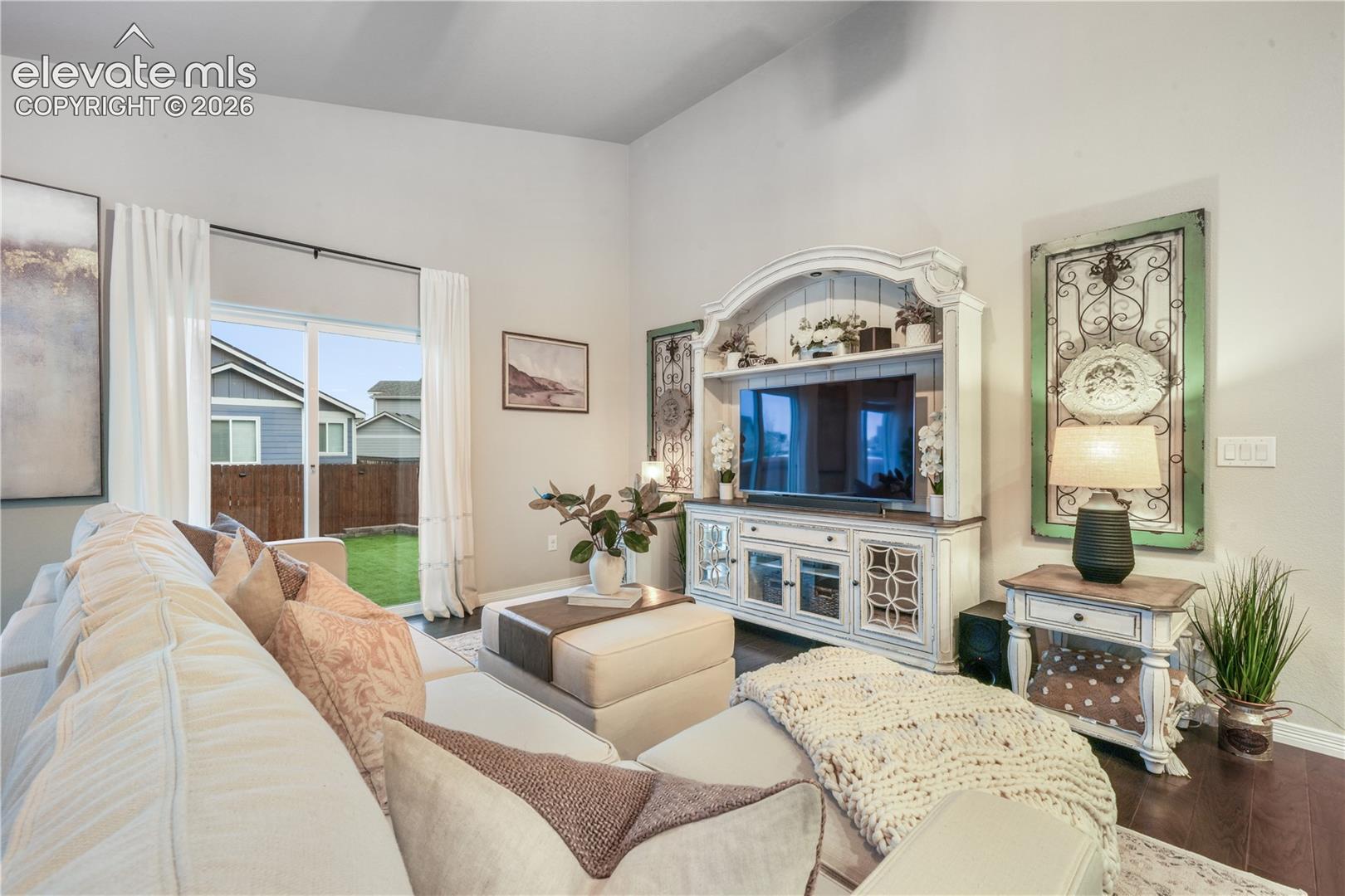 Spacious interior with vaulted ceilings, rich wood-finish flooring, and a sliding glass door providing access to the backyard
