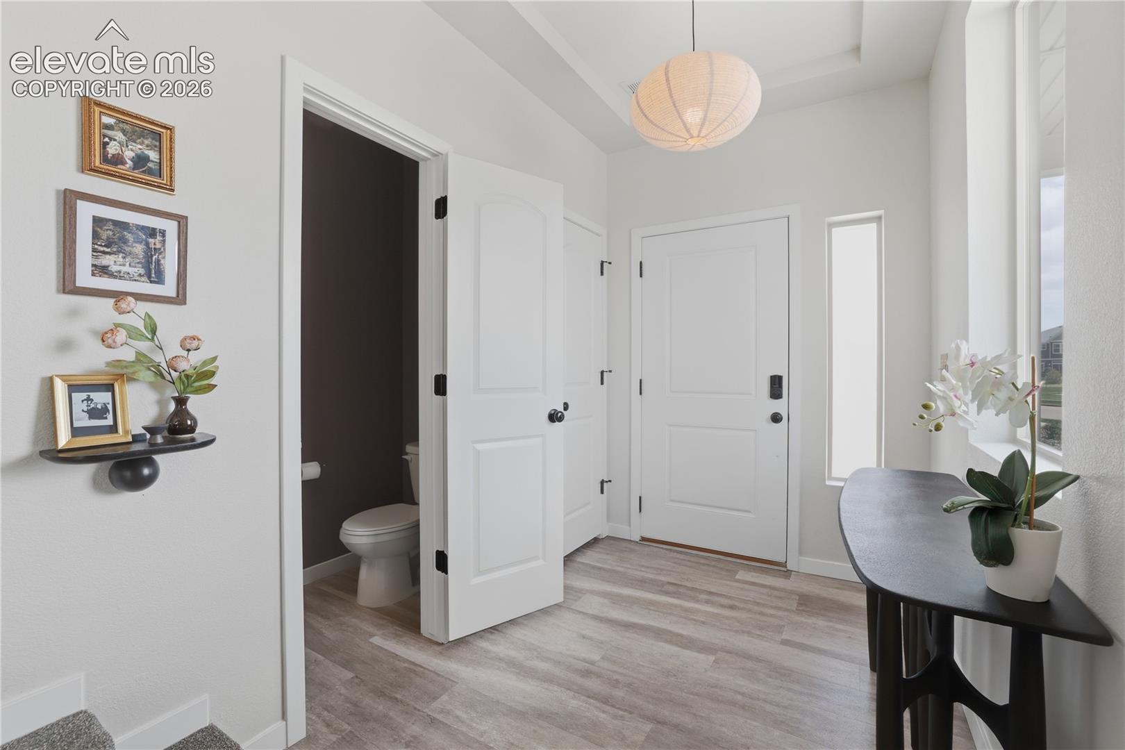Entryway featuring wood-finish flooring, a white paneled entry door, and a tall side window