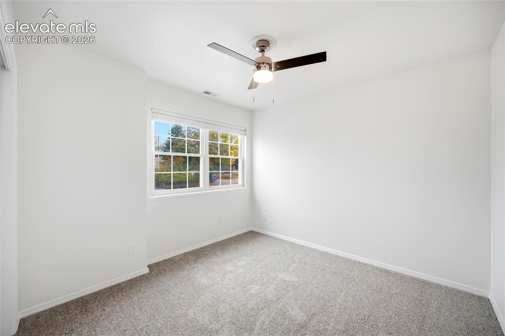 Neutral-toned carpeting, multi-pane window with white blinds, and central ceiling fan with integrated lighting