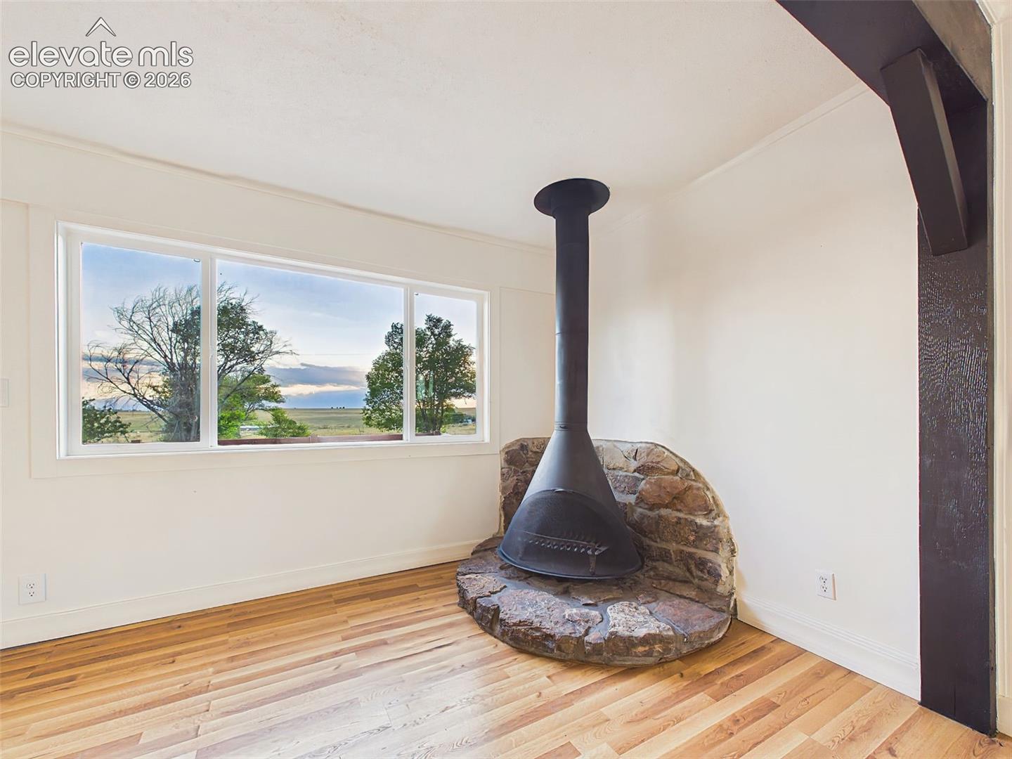 Fireplace – Freestanding wood-burning fireplace set on a rustic stone hearth creates a warm focal point while framing views of the surrounding landscape.
