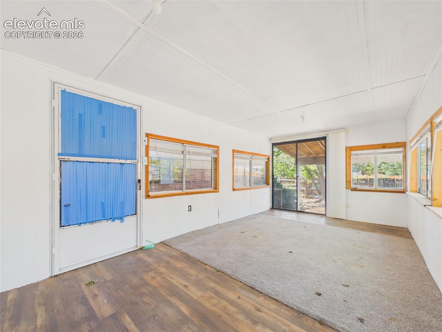 Additional view of the enclosed sunroom highlights abundant windows, flexible floor space, and direct access to the backyard.