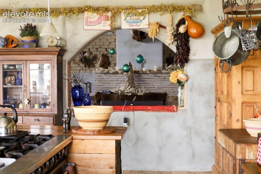 Rustic kitchen featuring a gas range, wooden cabinetry with glass inserts, and a built-in butcher block countertop