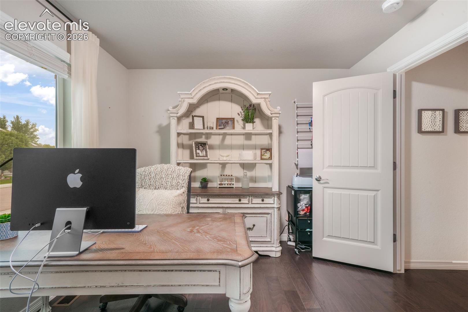 Hardwood flooring, painted interior door, window with white blinds, light wall color