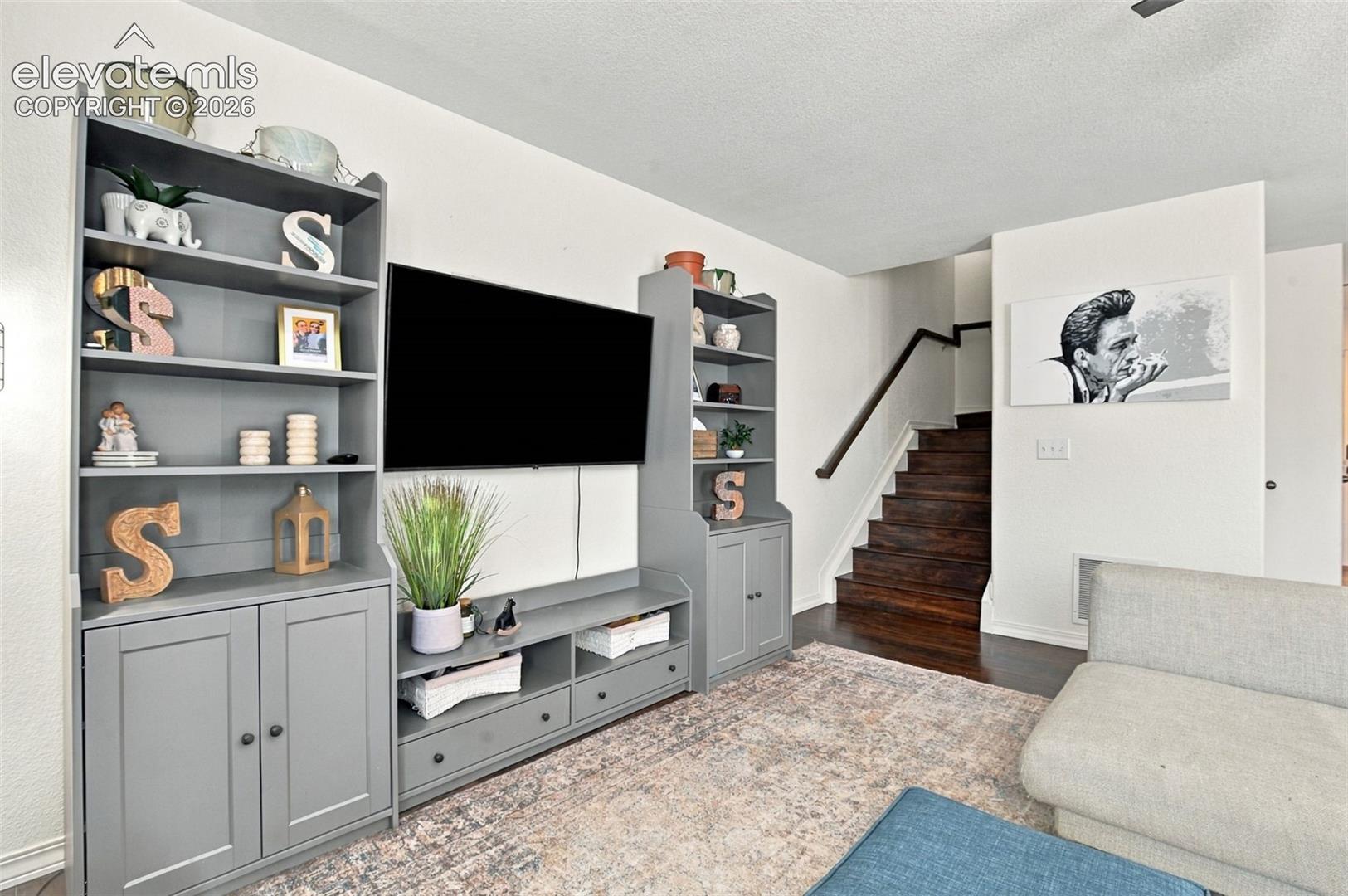 Integrated media console with shelving and cabinet storage, wood-finish staircase, and light wall finishes