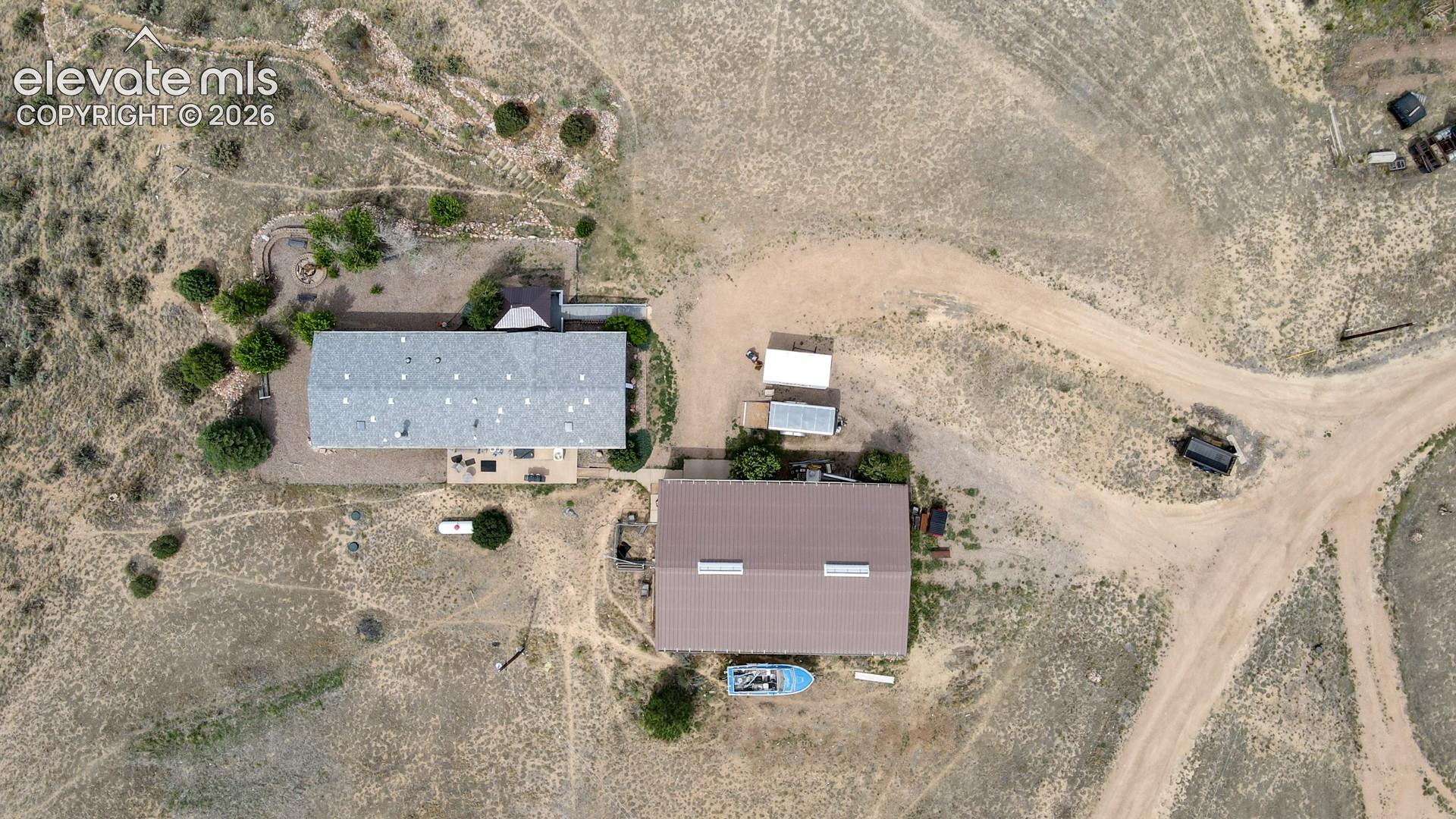 Expansive property featuring two distinct structures with pitched roofs, surrounded by natural terrain