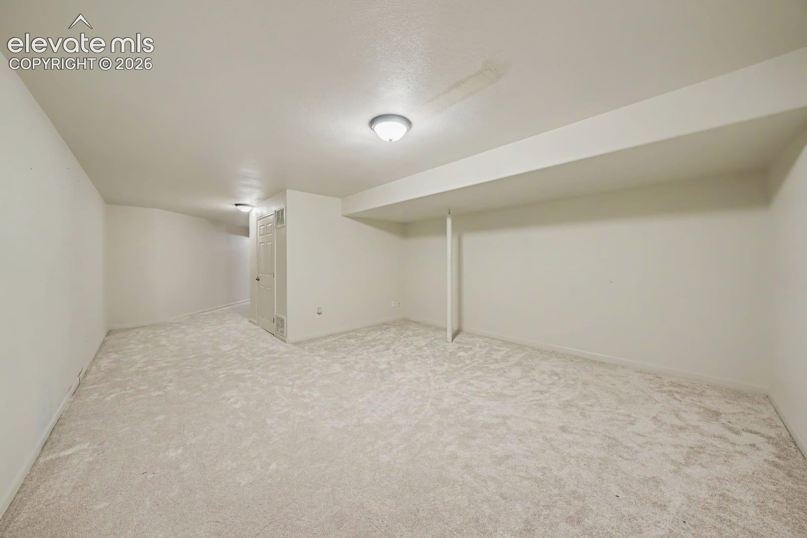 Spacious interior area featuring wall-to-wall carpeting, neutral-toned walls, and flush-mount ceiling lighting