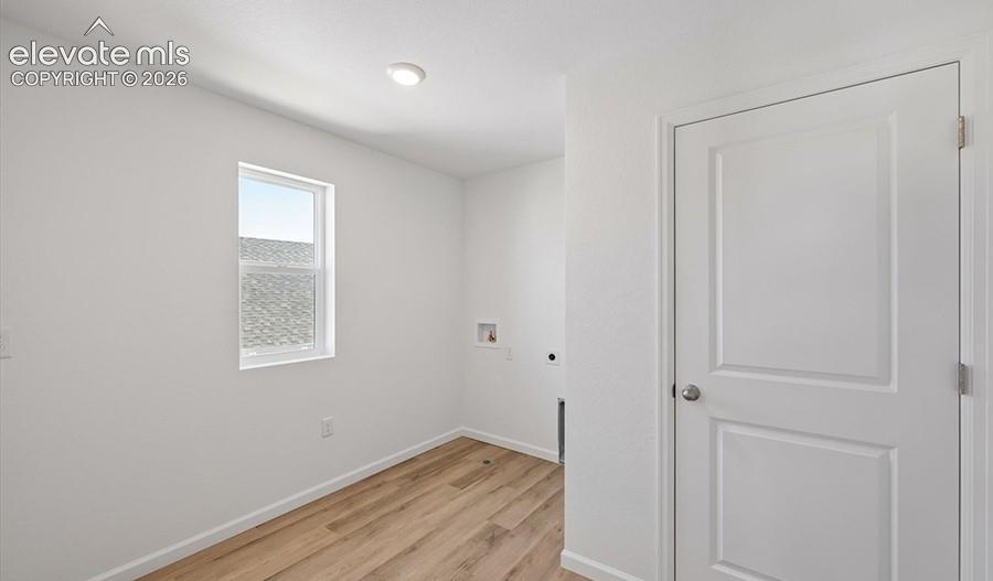 Room featuring wood-finish flooring, a single-pane window, flush-mount lighting, and a solid-core panel door